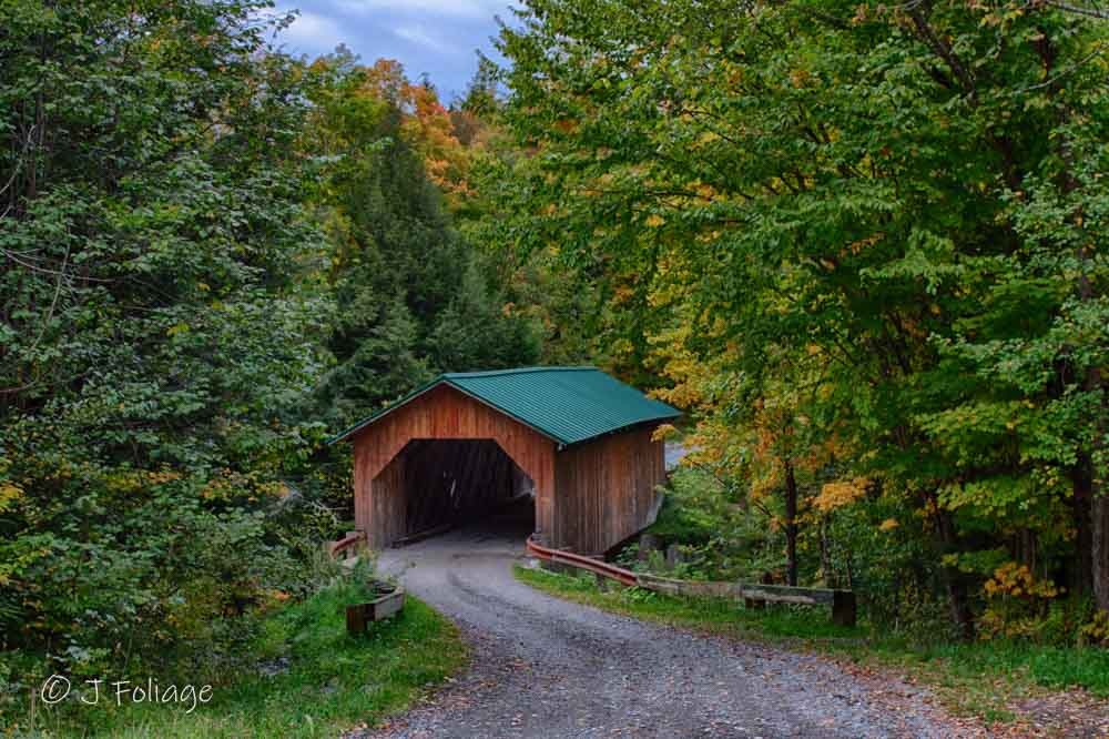 The West Hill Covered Bridge, also known as the Creamery Bridge, tucked into a lush Vermont forest setting.