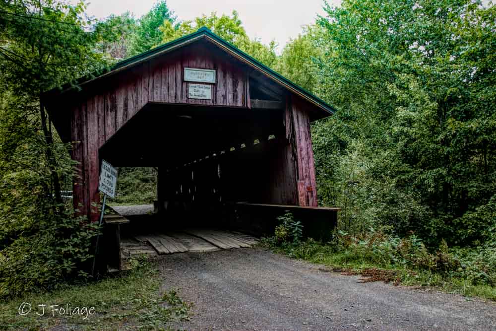 The historic Hutchins Covered Bridge, featuring its classic red-stained wood and surrounding greenery.