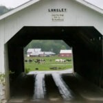 The Longley Covered Bridge in Montgomery VT, a white wooden bridge with cows grazing in the background