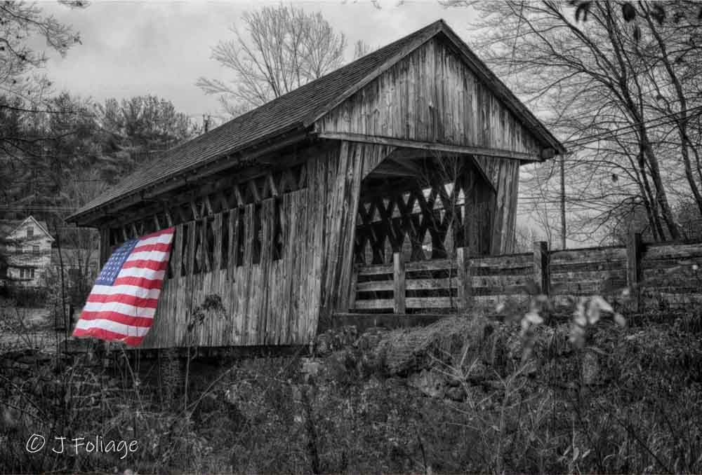 Selective color photograph of Cilleyville Bog Covered Bridge in black and white with a vibrant American flag as the focal point.