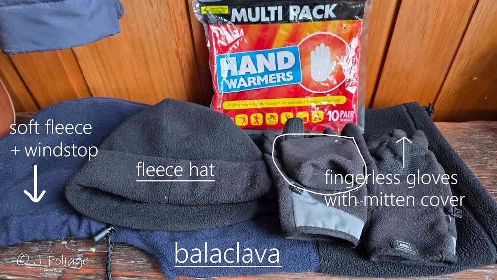 Extreme cold weather photography gear layout featuring a fleece balaclava black fleece hat and A 10-pack of multi-purpose chemical hand warmers essential for keeping fingers and camera batteries warm in the arctic-like-cold