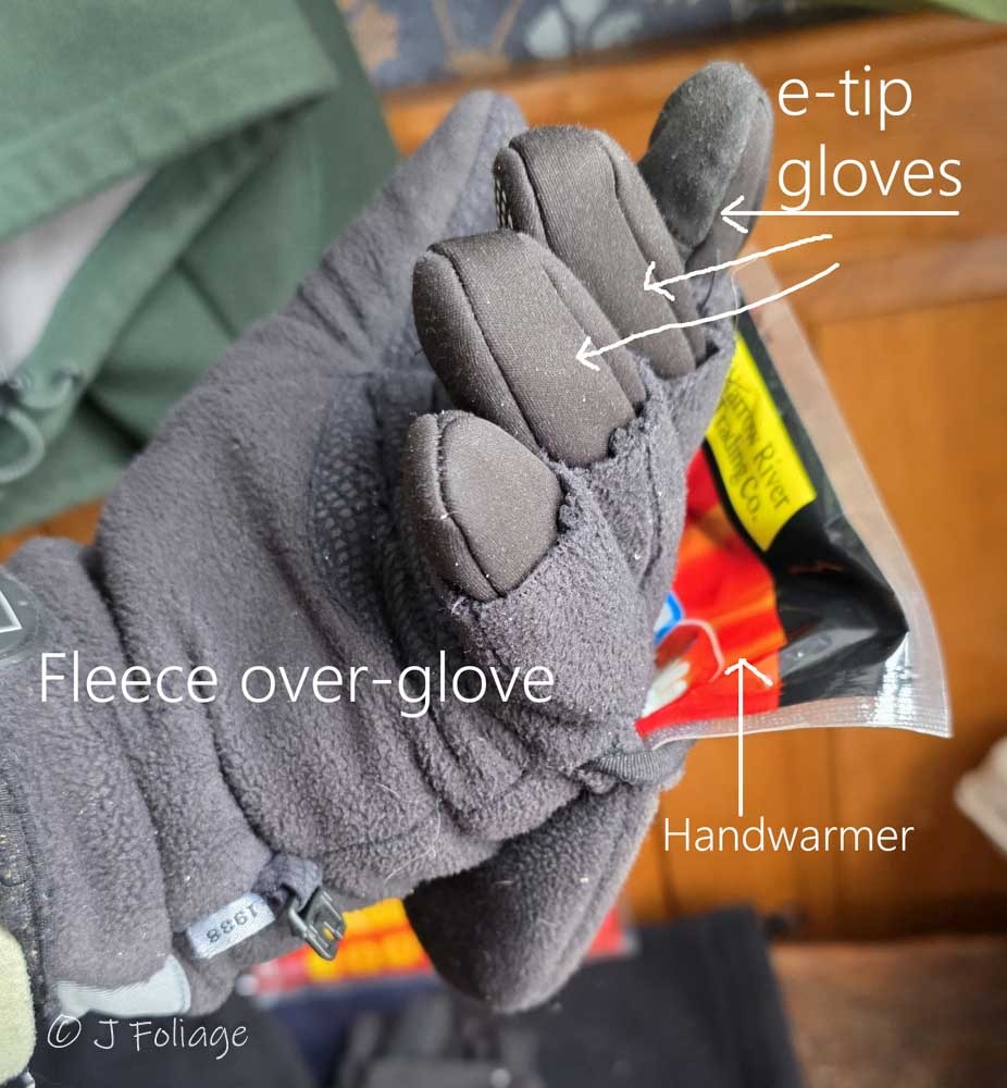 Close up of a photographer's hand wearing a thin black North Face e-tip liner glove used for operating smartphone screens in freezing weather