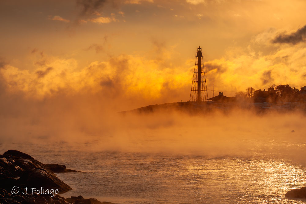 Morning sun filtering through thick sea smoke over Marblehead Harbor Massachusetts at sunrise