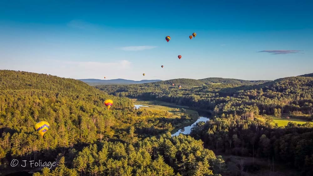 Aerial drone view of the winding Ottauquechee River near Quechee, Vermont, showing the scale of the valley during summer.
