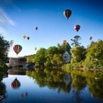 colorful hot air balloons reflecting in the water during the Quechee Balloon Festival morning launch.