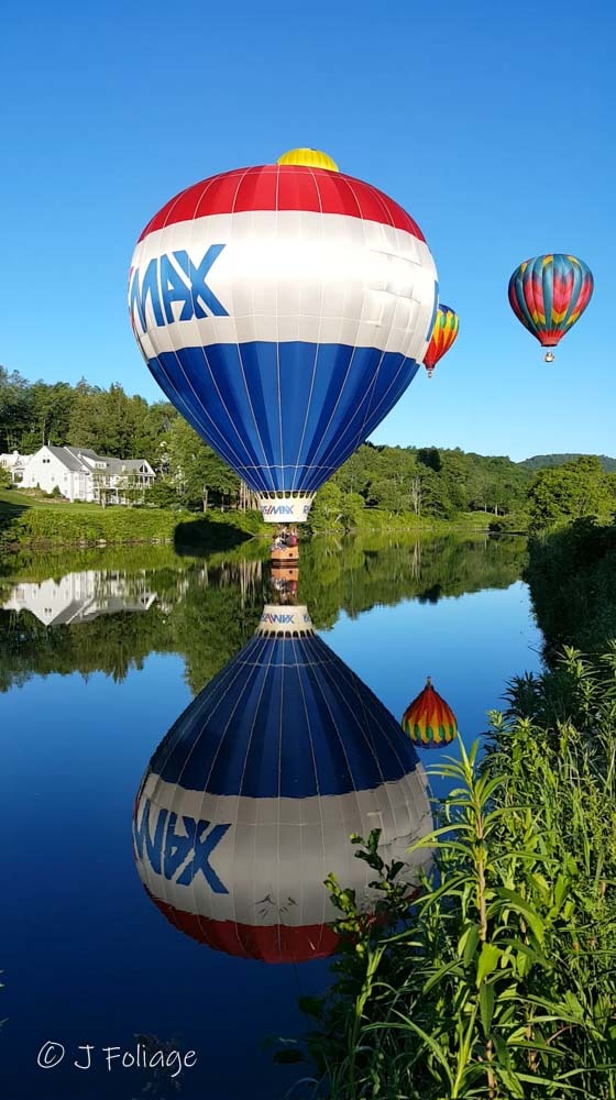 The RE/MAX hot air balloon performing a 'touch-and-go' on the water, creating a perfect reflection on the Ottauquechee River.