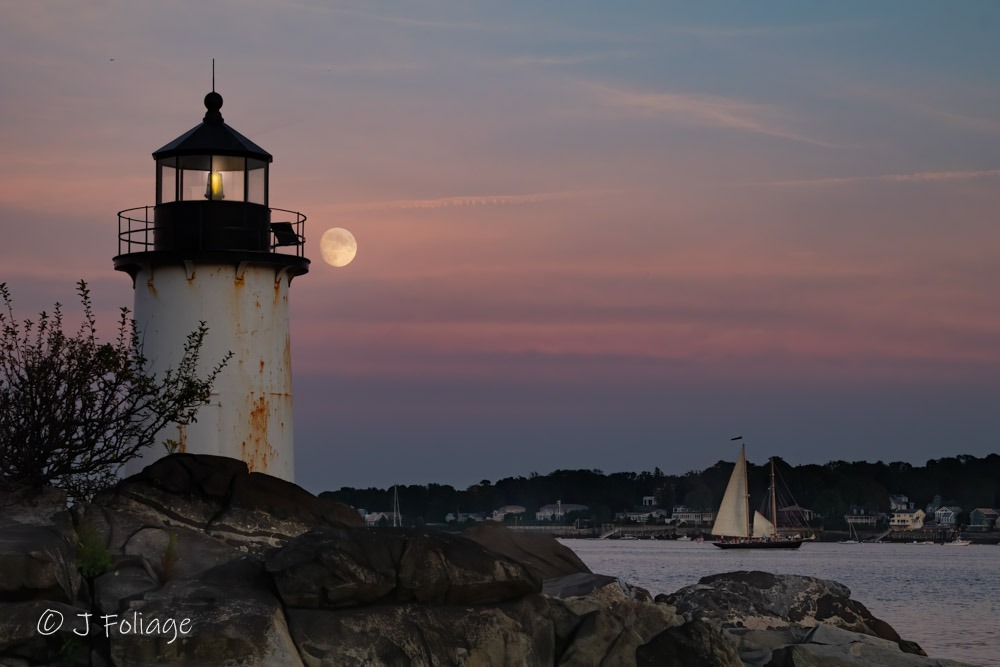 A full moon rises above the clouds past Salem's Lighthouse on Winter Island